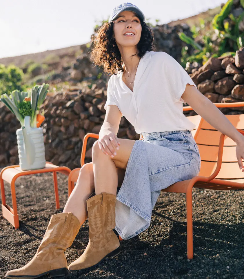 femme en chemisier blanc, jupe en jeans et santiag