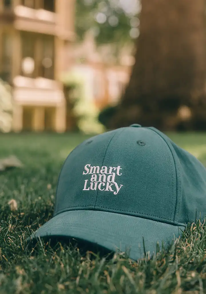 zoom sur une casquette verte sur laquelle est brodée 'Smart and Lucky' 