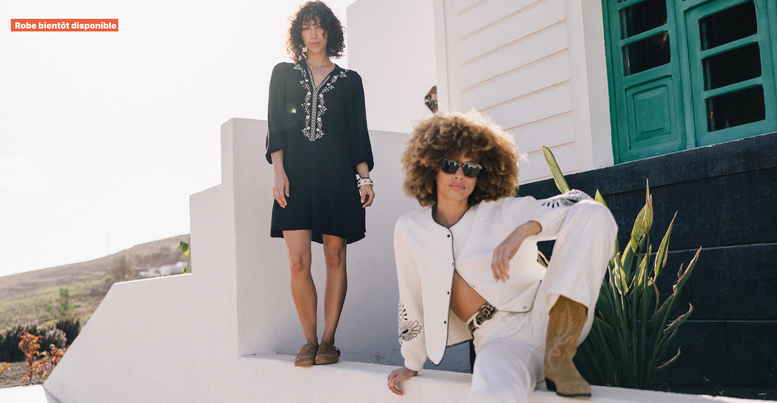 Visuel duo : femme debout en robe noire à broderies blanches et femme assise en jean blanc et veste blanche
