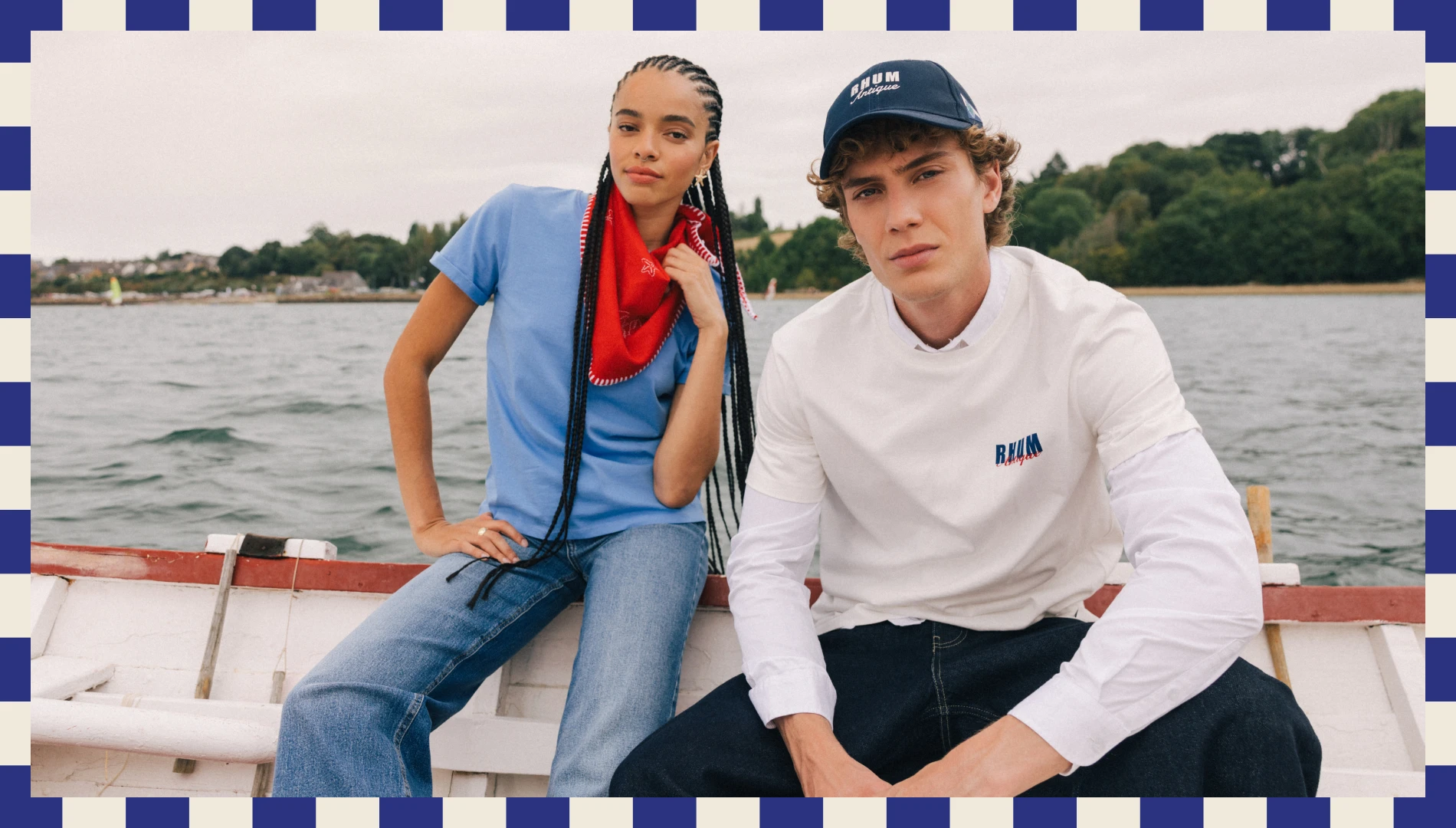 visuel mixte sur le bateau. La femme porte un jean, un tshirt bleu et un foulard rouge. L'homme porte un jean noir, un sweat blanc et une casquette bleu marine.